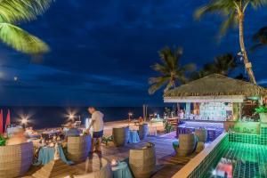 Samui Jasmine Resort - SHA Plus في شاطئ لاماي: رجل يقف أمام بار على الشاطئ في الليل