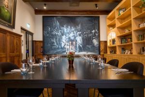 een tafel in een kamer met een groot schilderij aan de muur bij Hotel Die Port van Cleve in Amsterdam