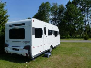 une remorque blanche garée dans une prairie dans l'établissement Erlebniscamping Lausitz - Campingplatz Ortrand / Camping Dresden, à Ortrand