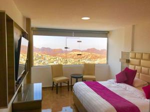 a bedroom with a bed and a large window at Petra Sella Hotel in Wadi Musa