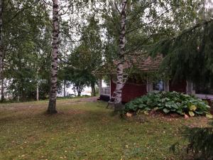 una casa con un banco frente a un patio con árboles en Rissalan Lomamökit en Juankoski
