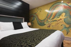 a bedroom with a large bed with a dragon painting on the wall at Le Monde Hotel in Edinburgh