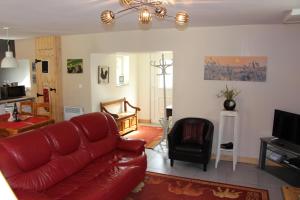 a living room with a red couch and a television at Cute Gite family Aucey Mont Saint Michel in Aucey-la-Plaine