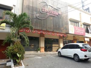 RedDoorz near Java Supermall Semarang في سيمارانغ: سيارة بيضاء متوقفة أمام مبنى