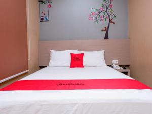 a bedroom with a red pillow on a white bed at RedDoorz near Java Supermall Semarang in Semarang