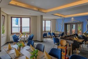un restaurante con mesas, sillas y ventanas en BE BIO Hotel be natural, en Tönning