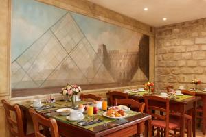 a dining room with tables and chairs and a large painting at Montparnasse Daguerre in Paris