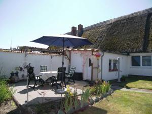 a patio with an umbrella and a table and chairs at Reethaus Natalie in Korswandt +26 photos