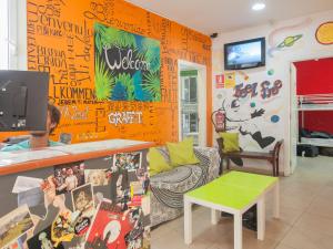 un soggiorno con una parete arancione con scritte sopra di No Limit Hostel Graffiti a Barcellona