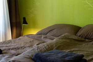 1 cama no hecha en un dormitorio con una pared verde en Momerooms – Appartement am Momering, en Oberwesel