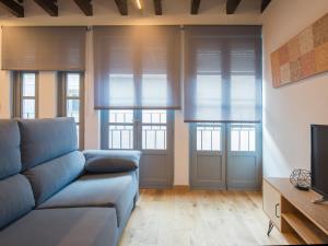 トレドにあるAldaba Apartamentosのソファと2つの窓があるリビングルーム