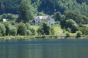 a house sitting on the shore of a lake at Eidfjord Gjestgiveri in Eidfjord