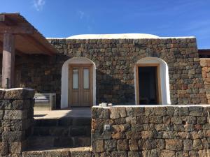 a stone building with a door and a stone wall at Dammuso Ma.Vi in Pantelleria