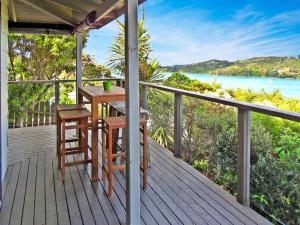 a wooden deck with a table and chairs on it at Twin Views in Oneroa