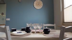 a dining room table with glasses and a clock on the wall at Apartament Centrum in Częstochowa