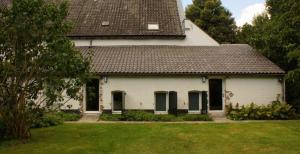 une maison blanche avec un toit marron et une cour dans l'établissement Het Kapelhuis, à Thorn