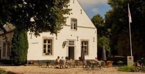 a group of people sitting at a table in front of a white building at Het Kapelhuis in Thorn