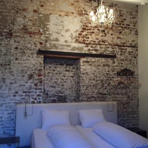 un divano bianco contro un muro di mattoni con un lampadario a braccio di Het Kapelhuis a Thorn