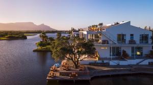 a large white house on the water next to a river at Marina Views in Muizenberg