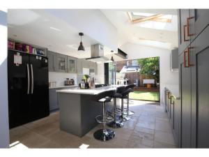 eine Küche mit einem schwarzen Kühlschrank und Barhockern in der Unterkunft Modern, Chic 2BR Townhouse in Central Oxford in Oxford