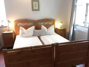 1 dormitorio con cama de madera y almohadas blancas en Weingärtner's Hof, en Sommerach