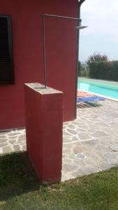 a red building with a light next to a pool at Casaletto In Maremma a Magliano in Magliano in Toscana