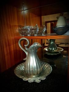 a silver vase sitting on a table with a plate at Casa Das Aguas Ferreas in Estação do Mogadouro