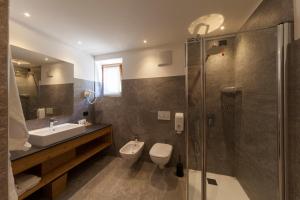 La salle de bains est pourvue de toilettes, d'un lavabo et d'une douche. dans l'établissement Rifugio La Montanara, à Molveno