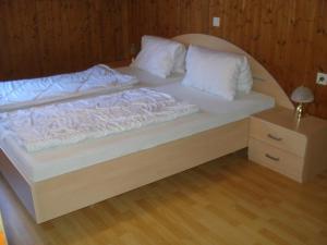 1 cama grande con sábanas blancas y almohadas. en Haus Mondspitze, en Bürserberg