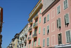 a facade of a pink building with green shutters at Be our Guests in Nice Port Bonaparte in Nice