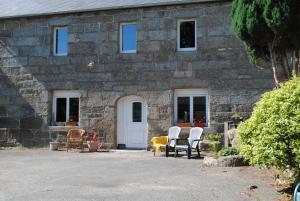 Maël-PestivienにあるMaison De Familleの椅子と白いドアのある石造りの建物