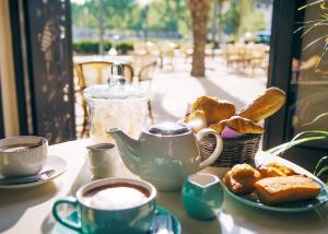 a table with cups of coffee and a basket of bread at Hôtel le XIX in Béziers +37 photos