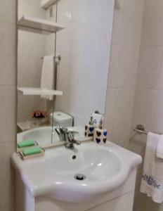 Baño blanco con lavabo y espejo en Apartamento da Praia da Amorosa en Amorosa