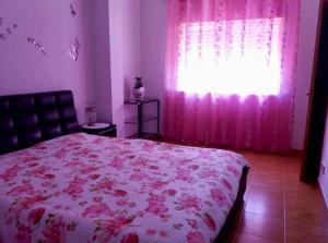 Schlafzimmer mit einem Bett und einem Fenster mit rosa Vorhängen in der Unterkunft Apartamento da Praia da Amorosa in Amorosa
