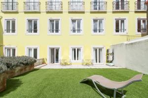 un grande edificio giallo con un cortile verde di Alfama - Lisbon Lounge Suites a Lisbona