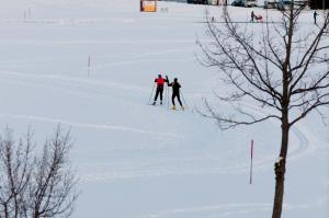 dos personas están esquiando por una pista cubierta de nieve en Steinhausers Hotel Hochbühl, en Oberstaufen