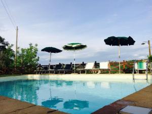 a swimming pool with tables and umbrellas and chairs at La Vecchia Camera in Montalcino