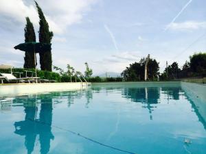 a large pool of blue water with an umbrella at La Vecchia Camera in Montalcino