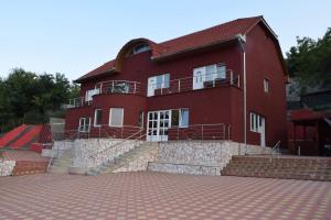 a large red house with a cobblestone driveway at Red House in Orşova
