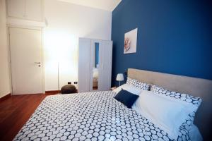 a person sitting on a bed in a blue bedroom at Quater Apartments - Milano in Milan