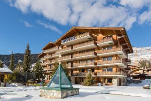a building with a christmas tree in the snow at Hotel Montpelier in Verbier