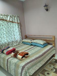 a bedroom with a bed with two pillows and a window at Homestay Pulau Langkawi in Pantai Cenang