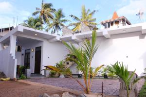 een wit huis met palmbomen ervoor bij Turtle Reef Guest in Mirissa