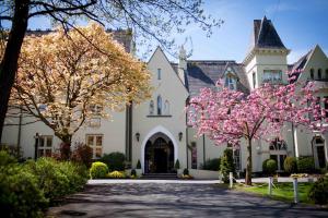 a white house with pink flowering trees in front of it at Glen-Yr-Afon House Hotel in Usk