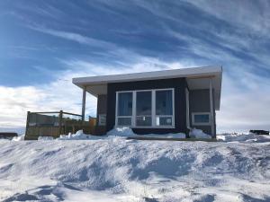 uma pequena casa na neve em frente em Blue View Cabin 3A With private hot tub em Reykholt
