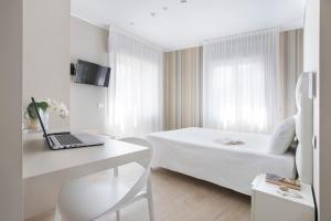 a white room with a bed and a laptop on a desk at Residence Dolcemare in Laigueglia