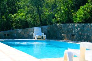 a swimming pool with a blue chair at Cabañas El Arcano in Capilla del Monte