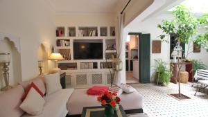 a living room with a white couch and a tv at Riad Kasbah Baraka in Marrakesh