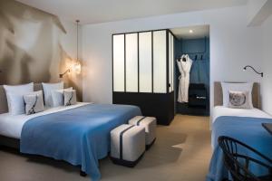 a hotel room with two beds with blue sheets at Hôtel Les Deux Girafes in Paris