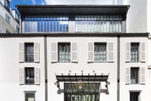 パリにあるホテル レ ドゥ ジラフの白い建物(黒い窓、バルコニー付)